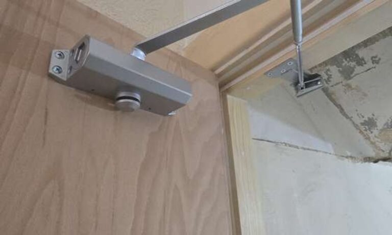 Overhead door closer adjusted during a fire door maintenance visit